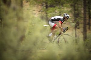 Specialized Bikes promotional image: Man in biking gear riding Specialized bike through forest Specialized Bikes promotional image: Man in biking gear riding Specialized bike through forest